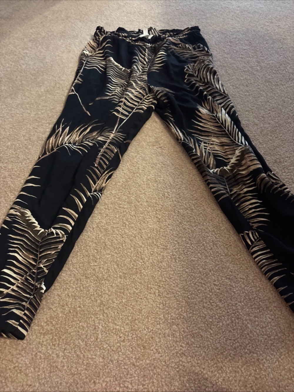 H&M black and beige pull-on pants featuring a palm leaf or tropical print. US 8